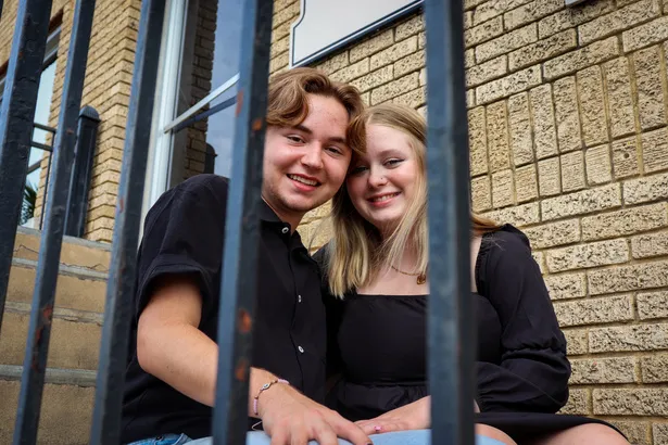 Two friends smiling behind an iron gate